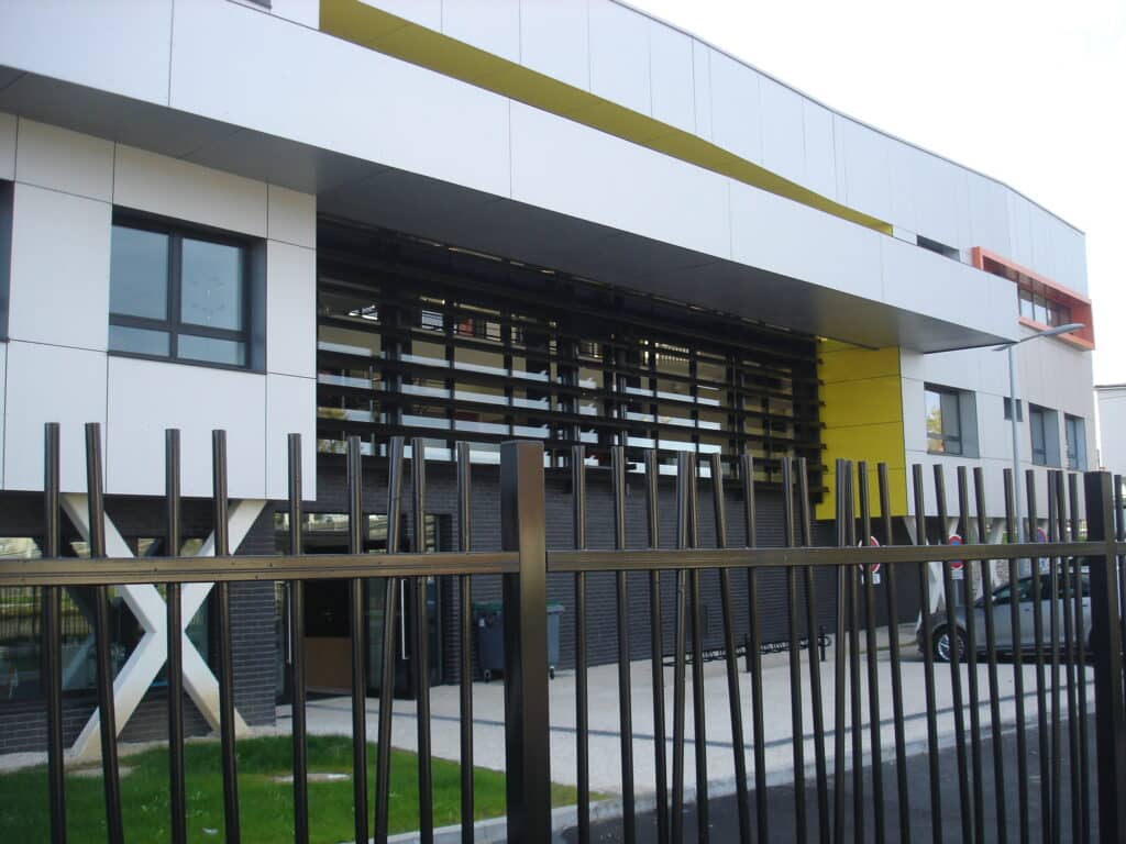 Photo du bâtiment du centre social Multi-Accueil à Tergnier dans le 02 côté parking avec grille noire